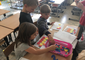 Uczniowie układają wzory z kolorowych figur.